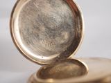 a close up of a gold pocket watch on a table