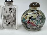 two small glass bottles with asian paintings on them sitting next to each other