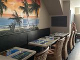 des tables et des chaises dans un restaurant dont le mur est orné d'une fresque représentant des palmiers