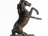 statue of a horse rearing up on its hind legs on a wooden base