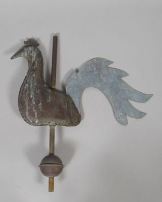 a metal rooster on a pole on the wall