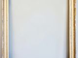 an empty picture frame hanging on a wall with a white background