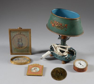 une table sur laquelle se trouvent une lampe, un cadre photo, une horloge, un tableau et une image représentant un squelette