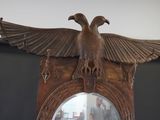 a mirror with a bird on it and a man standing in the background