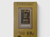 un gros plan d'un lingot d'or dans un emballage posé sur une surface blanche
