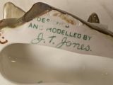 a hand holding a porcelain shoe with writing on it