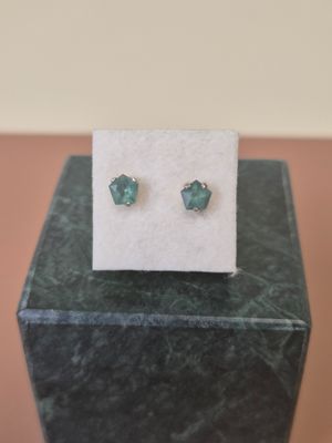 a pair of earrings sitting on top of a marble block