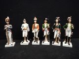 five figurines of men in military uniforms are lined up on a black surface