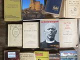 several books are stacked on a table in front of a window