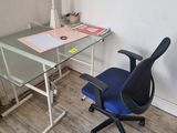 un bureau en verre avec une chaise bleue devant