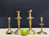 three brass candlesticks and a green apple on a table
