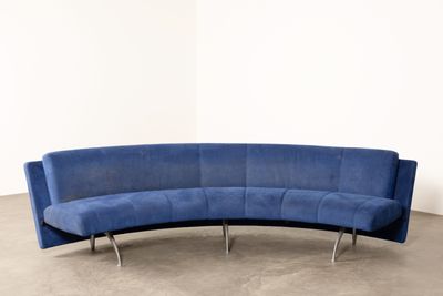 blue curved sofa in a white room with concrete flooring