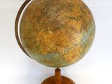 un vieux globe terrestre posé sur un socle en bois, sur fond blanc