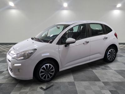la petite voiture blanche est garée sur un sol en damier