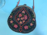 a black purse with pink flowers on it on a blue table
