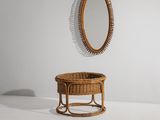 un miroir ovale accroché au mur au-dessus d'un panier en osier