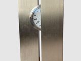 une horloge en métal posée sur un socle, sur fond blanc