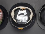 three hats are lined up on a black surface, one is black and the other is green