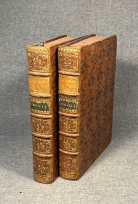 two old books sitting on top of each other on a table