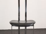a black chair sitting on top of a gray floor next to a white wall