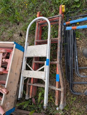 a pile of old chairs and ladders sitting on the ground