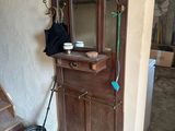 une armoire en bois avec un miroir et un balai posé par terre