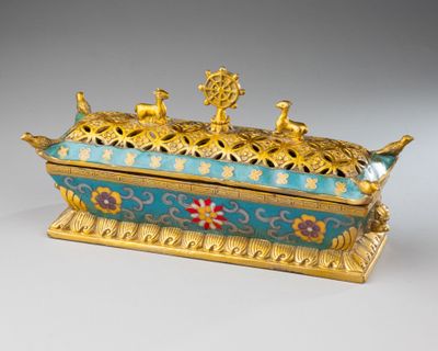 une boîte dorée et bleue ornée d'oiseaux, posée sur une table