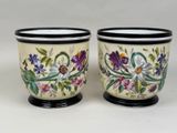 two cups with flowers painted on them sitting on a table