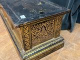 an old wooden box with a black and gold design on it