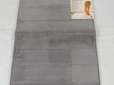 grey bath mat with a tag on it sitting on a white surface