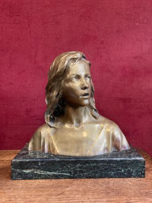 statue of a woman sitting on a table with a red wall behind her