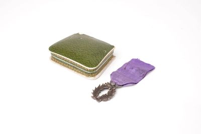 un ruban violet et un petit étui vert posés sur une surface blanche