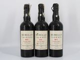 trois bouteilles de vin rouge posées l'une à côté de l'autre sur une surface blanche