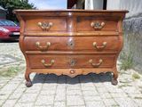 une commode ancienne sur roulettes devant un immeuble