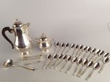 many silver spoons and a silver teapot on a table