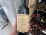 a person holding a bottle of wine in front of a refrigerator