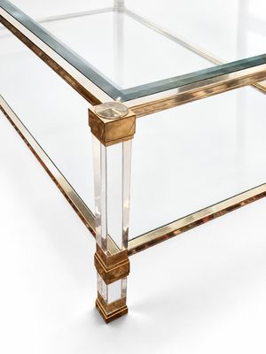 a glass coffee table with a gold base and a clear glass top