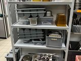 une étagère sur laquelle sont posés de nombreux récipients et casseroles, dans une cuisine