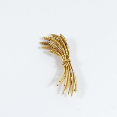 une broche en or représentant des épis de blé sur un fond blanc
