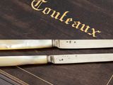 two knives sitting on top of a book on a table