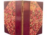 une image représentant un livre rouge aux bords dorés et orné d'un motif floral