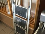 a metal hand truck with two steps next to a window
