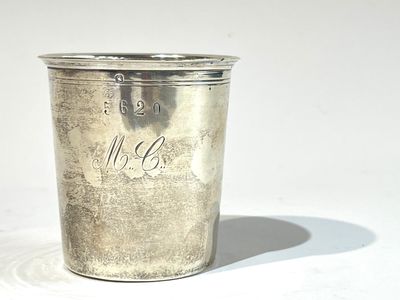 une tasse en argent posée sur une table à fond blanc
