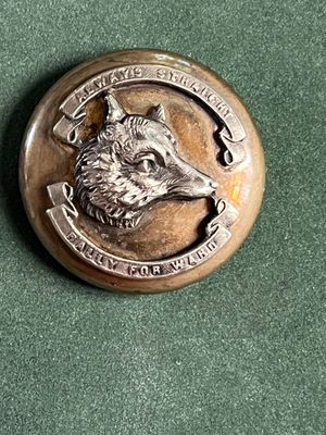 un badge en métal sur lequel est représenté un loup
