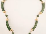 a necklace with green beads and gold accents on a white background