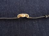 a close up of a black cord with a gold clasp on it