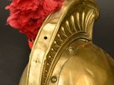 a gold helmet with a red flower in it