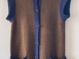 gilet sans manches marron et bleu avec des poches, suspendu à un cintre