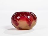 a red and gold vase sitting on a white surface