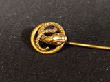 a close up of a gold brooch with a snake on it